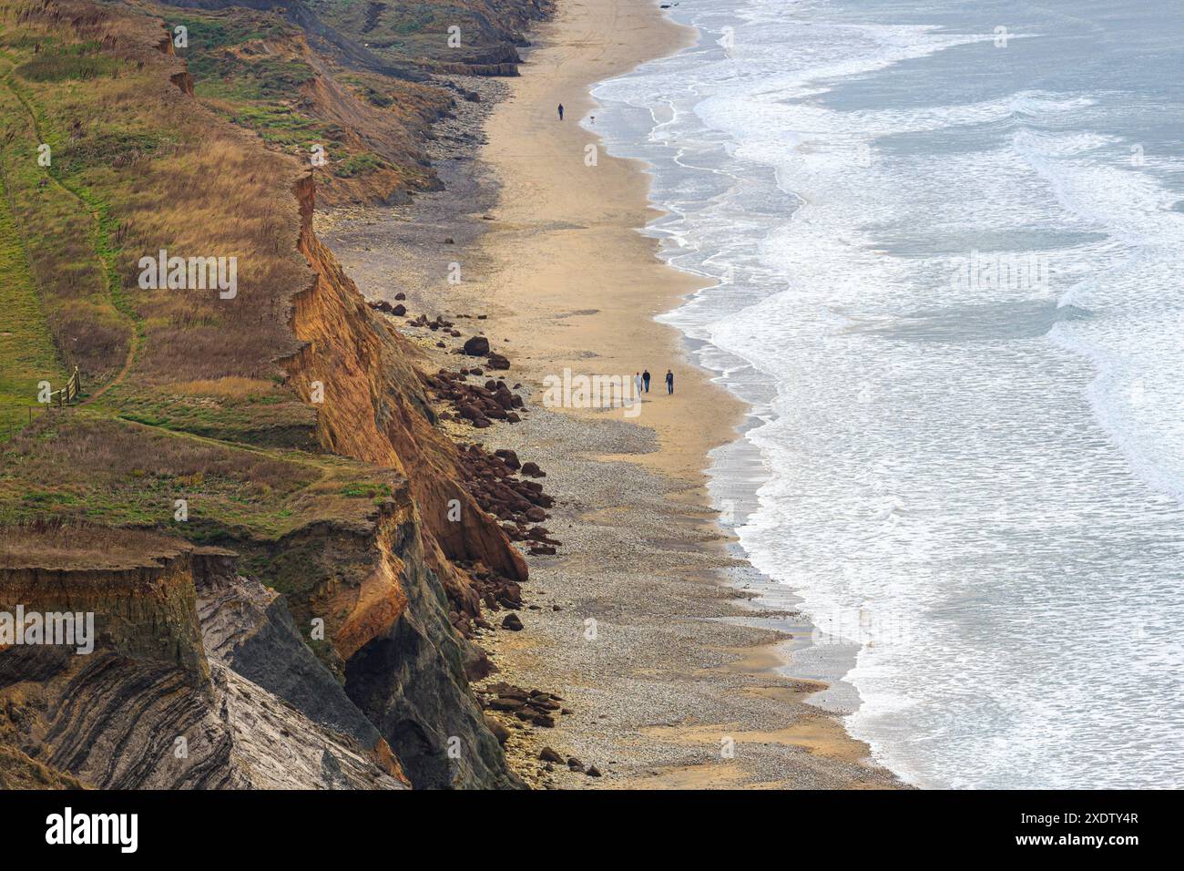 Leute, die am Strand mit abgesenkten Klippen spazieren gehen, Compton Down, Isle of Wight, Großbritannien Stockfoto