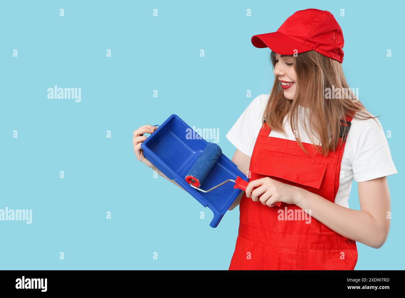 Malerin mit Malerwalze und Tablett auf blauem Hintergrund Stockfoto