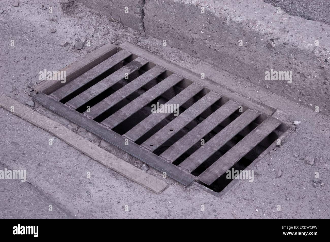Ein rostiges, schmutziges Sturmrost mitten auf einer Asphaltstraße Stockfoto