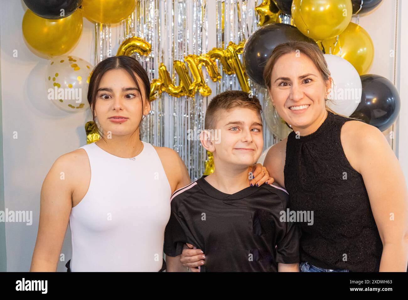 Junge Geburtstagskinder, begleitet von ihrem kleinen Bruder und ihrer Mutter. Stockfoto