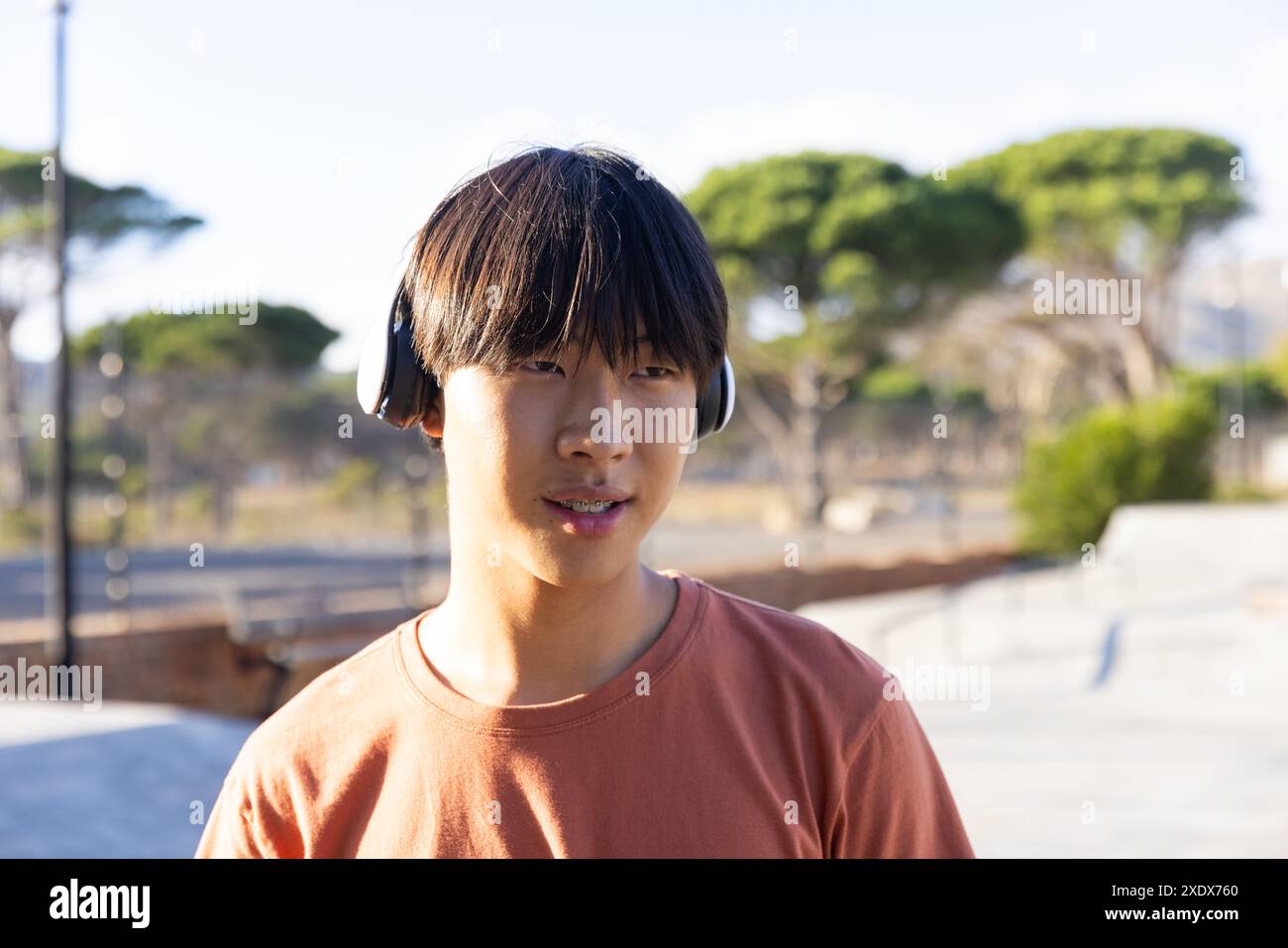 Musik mit Kopfhörern hören, Teenager mit Freunden im Freien verbringen Stockfoto