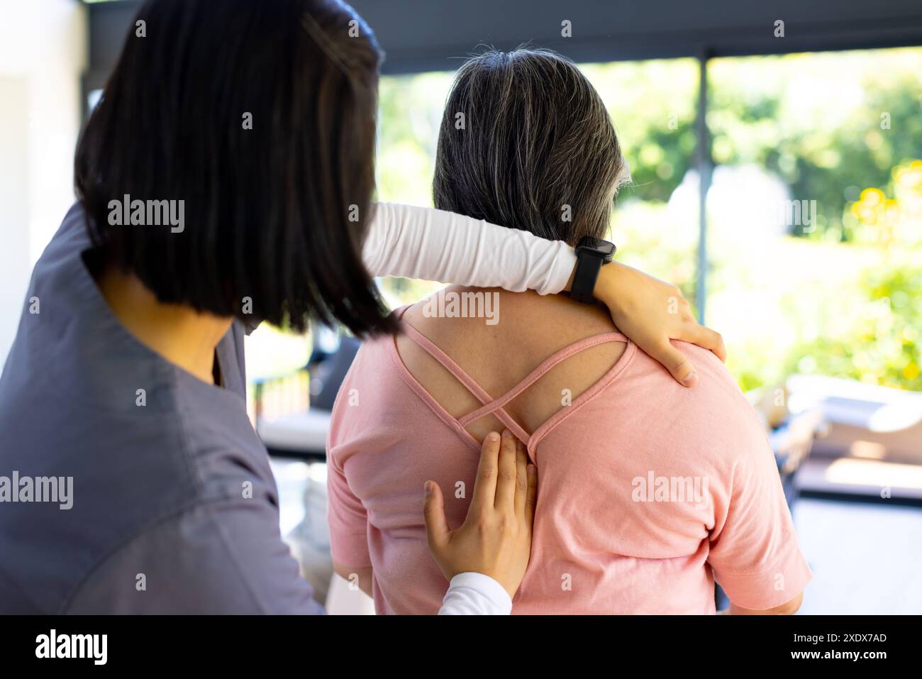 Physiotherapeut hilft Seniorinnen bei Rückenübungen zu Hause Stockfoto