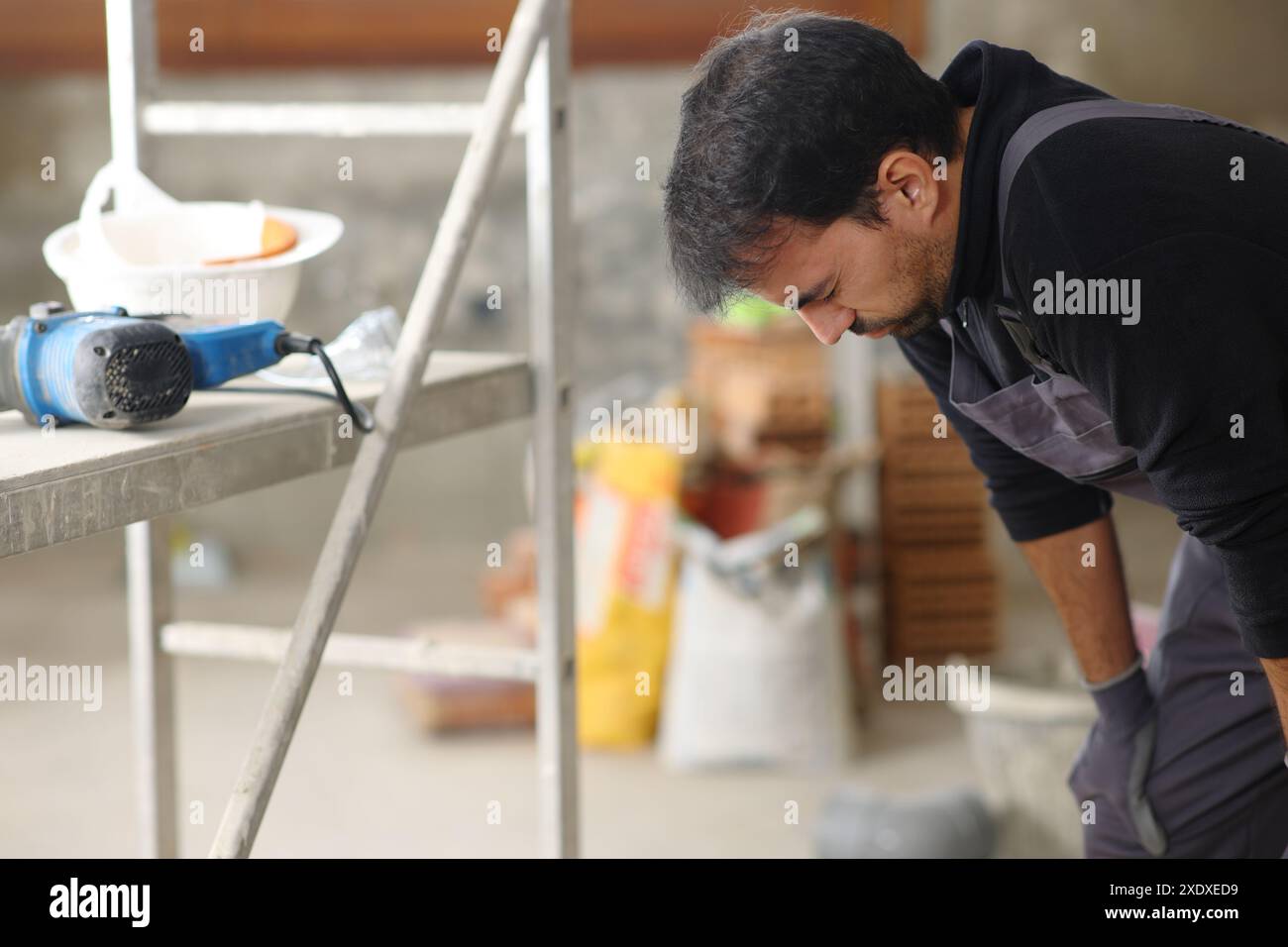 Müde Bauarbeiter, die sich nach der Arbeit in einem Haus ausruhen und beschweren Stockfoto