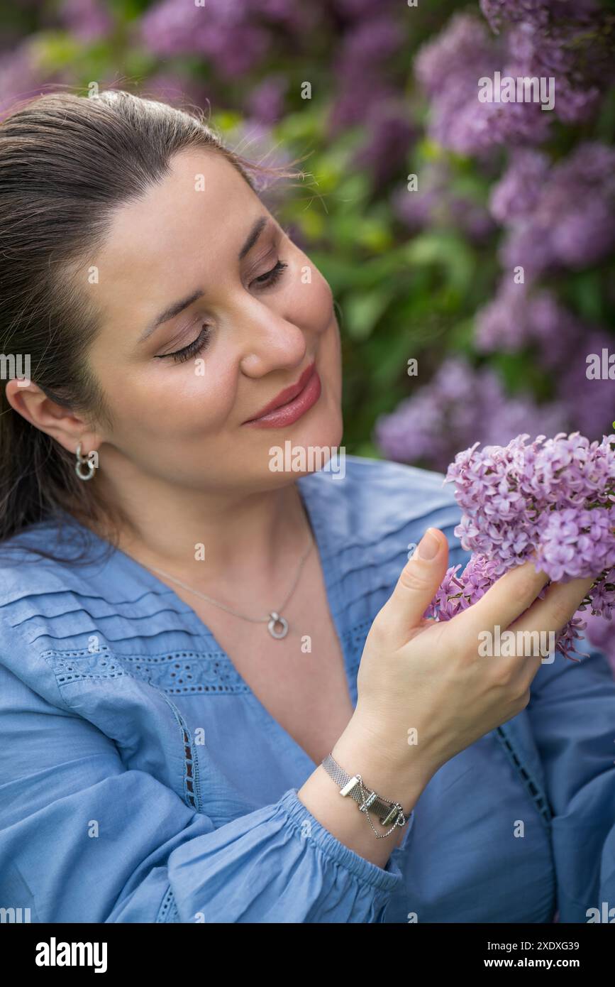 Porträt eines süßen, glücklichen Mädchens. Schwangere Frau nahe Flieder. Nahaufnahme. Schwangerschaft. Warten auf das Baby. Stockfoto