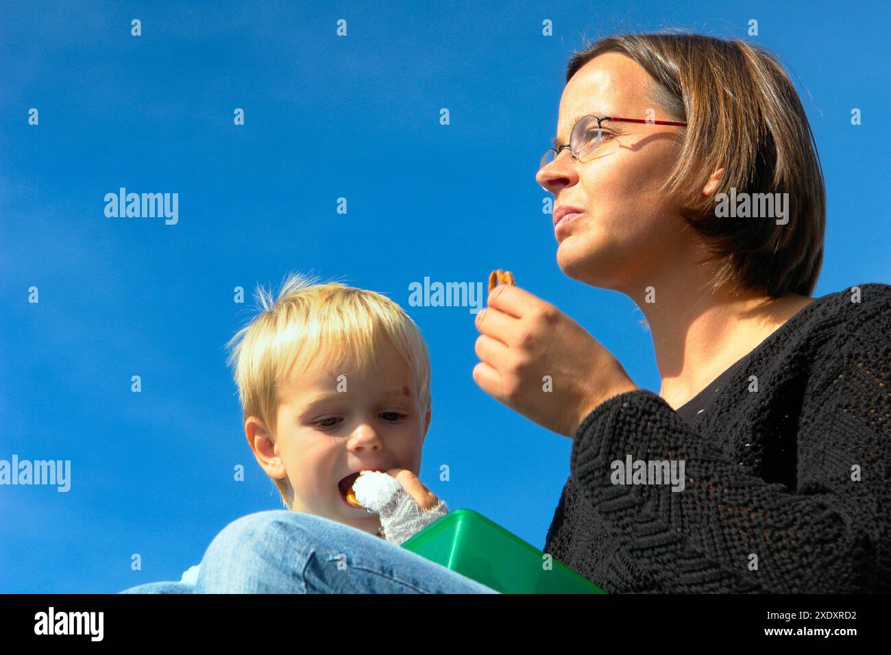 Mutter und Sohn sitzen in der Mittagssonne Stockfoto