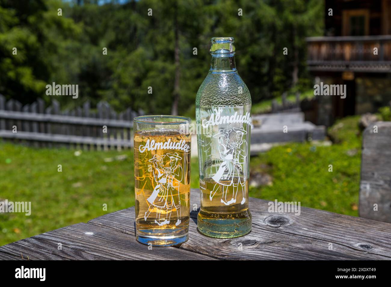 Ein Glas und eine Flasche Almdudler stehen auf einem Tisch vor der Filzmoosalm im Großartltal, Salzburg, Österreich. Die 1957 eingeführte Kräuterlimonade ist eine der bekanntesten Softgetränke Österreichs. Stockfoto