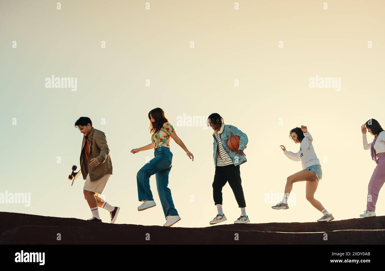 Eine Gruppe von Freunden, die gemeinsam in der Sonne spazieren, sich vor Freude vorwärts bewegen und den unbeschwerten Geist der Jugend und des Spaßes genießen. Stockfoto