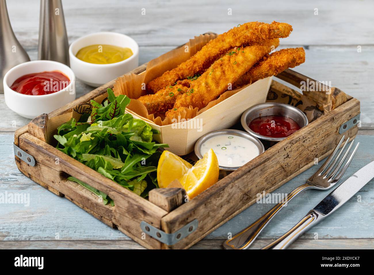 Fish and Chips mit frischem Gemüse und Saucen auf Holztisch Stockfoto