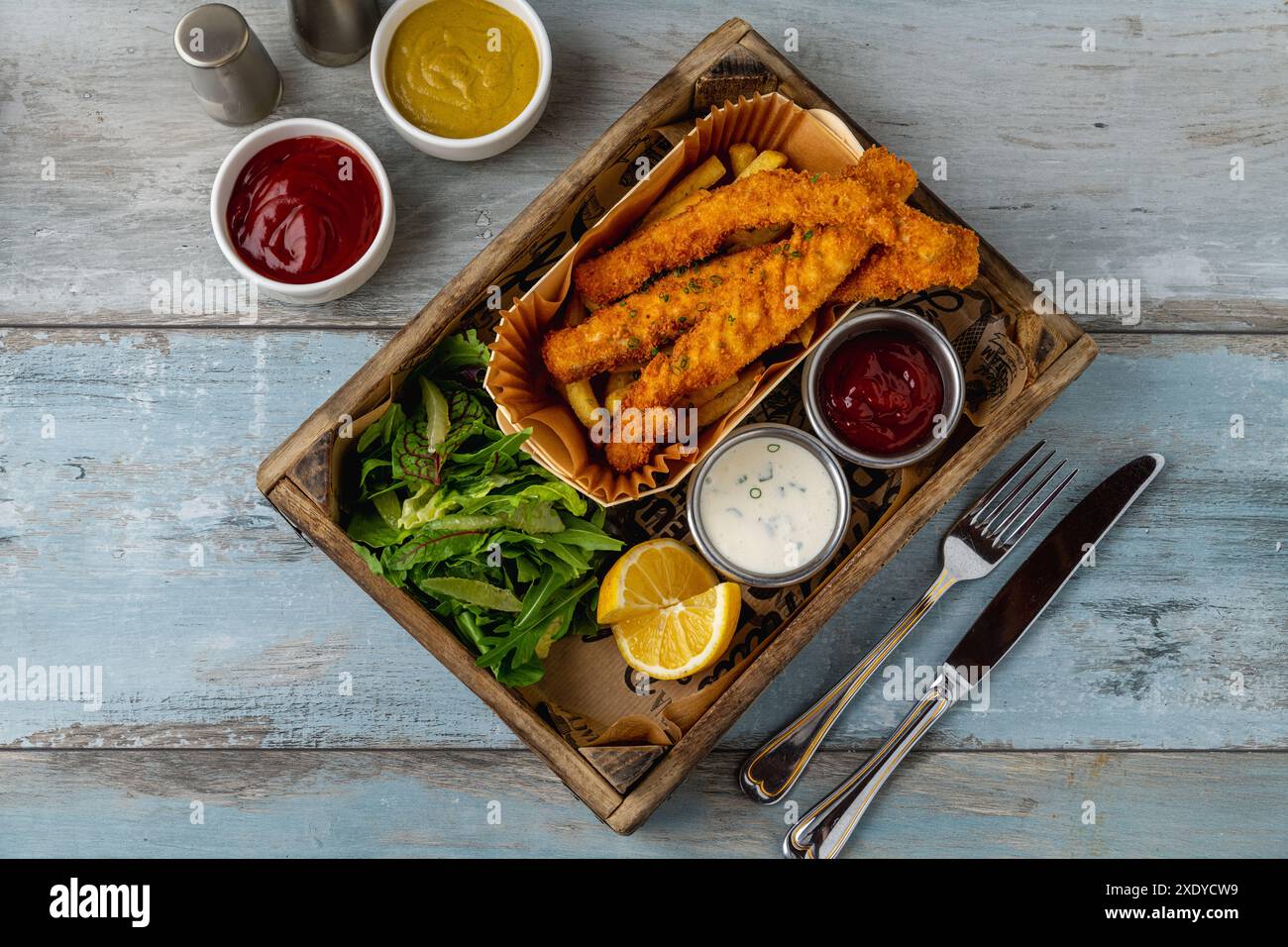 Fish and Chips mit frischem Gemüse und Saucen auf Holztisch Stockfoto