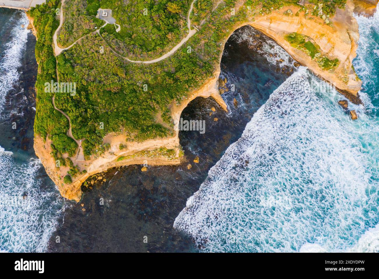 Aus der Vogelperspektive von Wellen, die in felsige Höhlen einbrechen, die in Küstenklippen erodiert wurden, in Port Campbel an der Great Ocean Road in Victoria, Australien Stockfoto