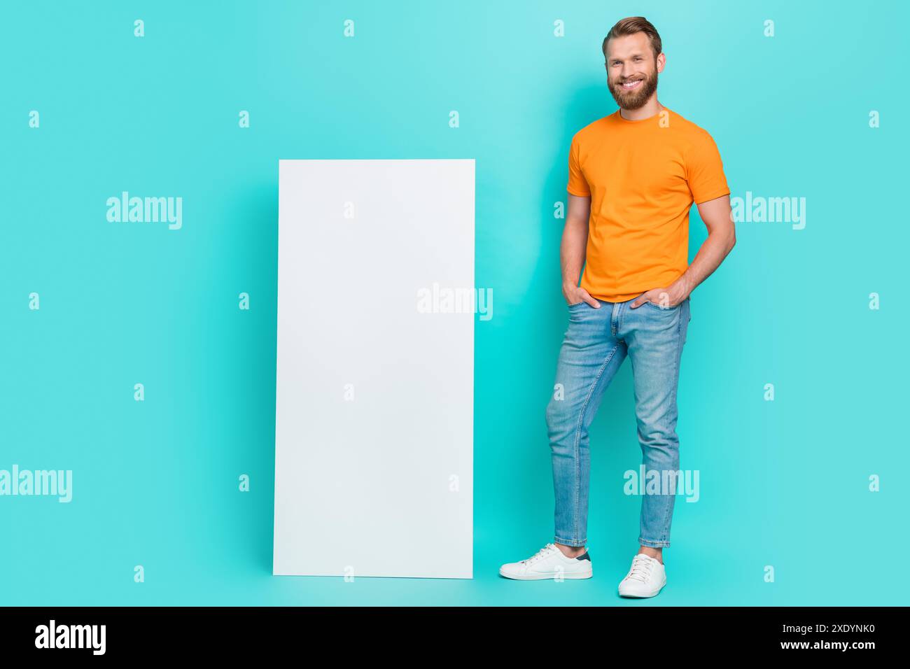 Foto in voller Länge von einem netten Bartmann, der in der Nähe des Telefons steht, tragen T-Shirt Jeans Stiefel isoliert auf türkisfarbenem Hintergrund Stockfoto