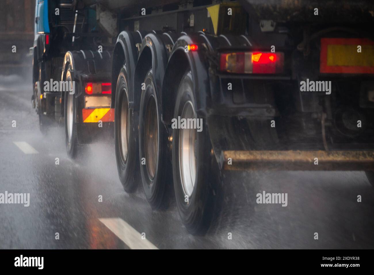 Regenwasser Spritzer fließen von Rädern von schweren LKW schnell bewegen sich bei Tageslicht Stadt mit selektivem Fokus. Stockfoto