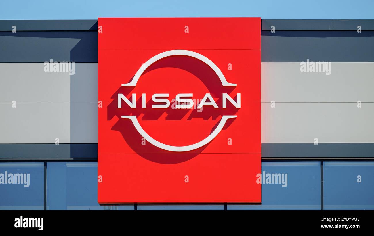 Nissan. Eine rote Plakatwand mit dem Nissan-Logo auf einem blauen Himmel Hintergrund. Stockfoto