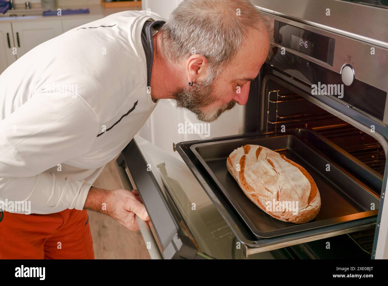 Mann, der Brot in den Ofen stellt Stockfoto