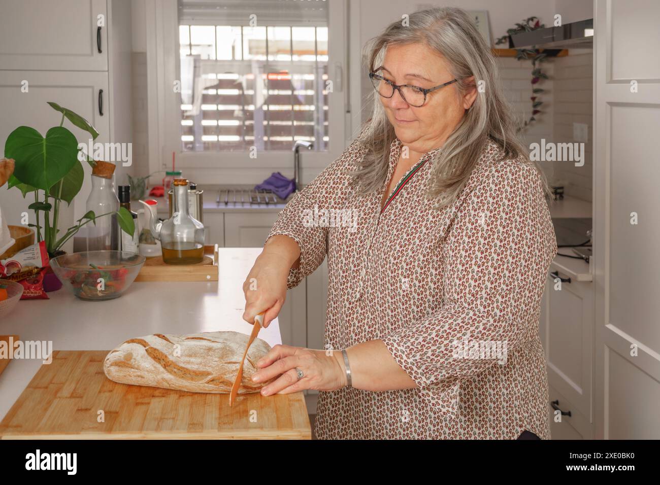 Frau schneidet Scheiben von frisch gebackenem Brot Stockfoto