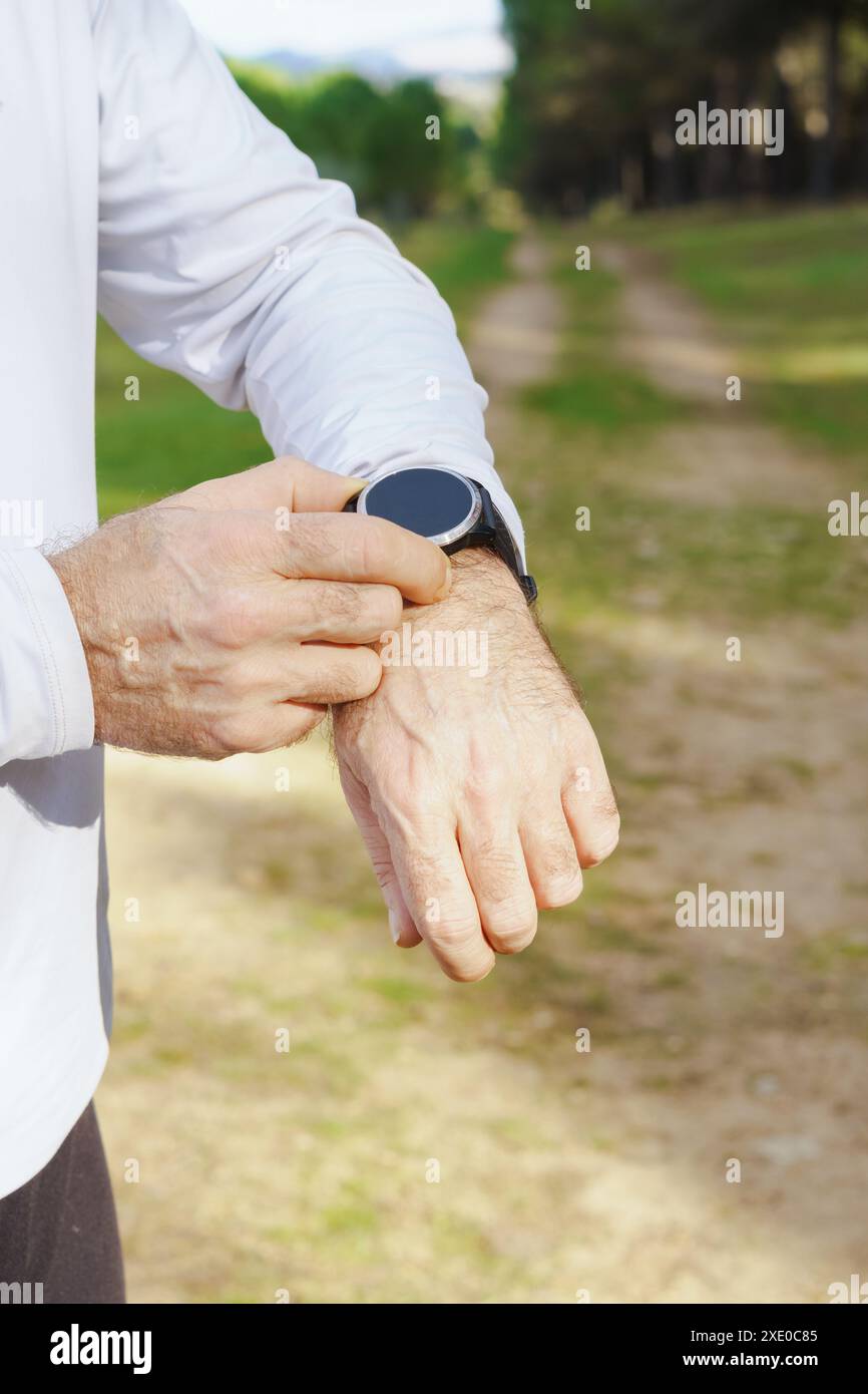 Mann trainiert mit seiner Smartwatch im Feld Stockfoto