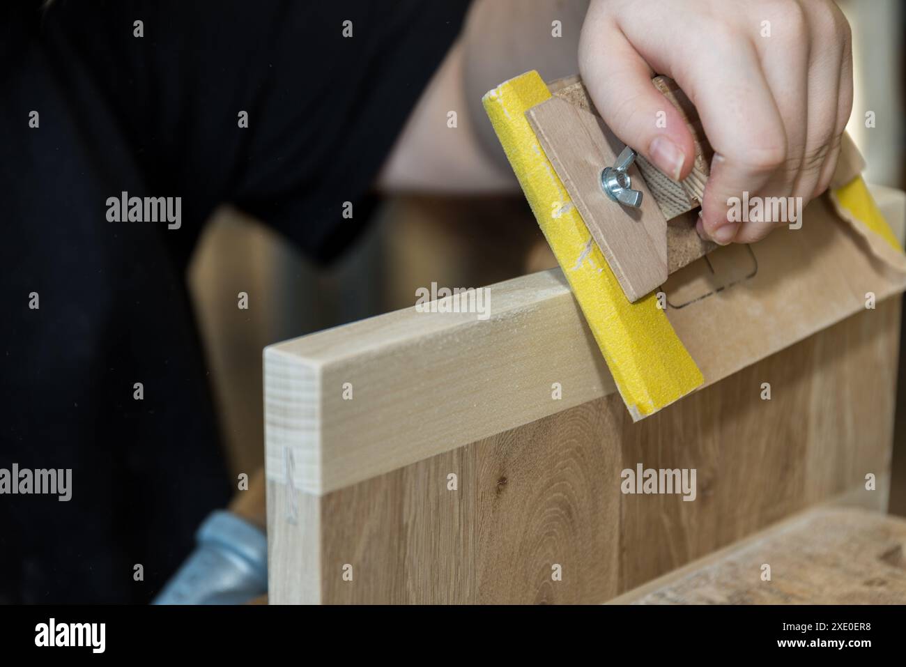 Schleifen von Holz mit Schleifpapier auf dem Schleifblock als Werkzeug Stockfoto