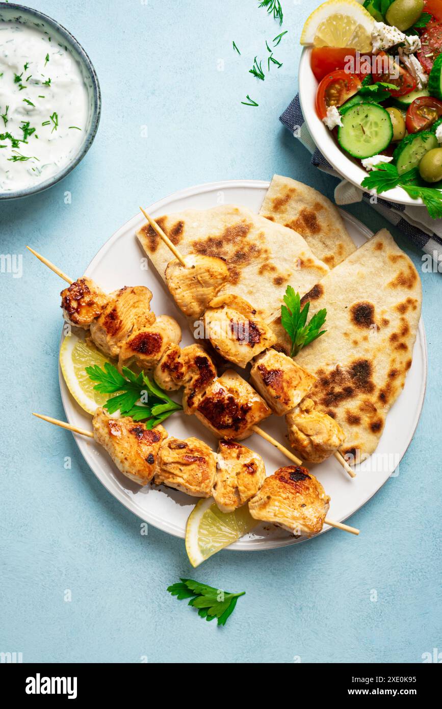 Hühnchen-Souvlaki-Kebabs, Kräuterjoghurtsauce und Pita-Fladenbrot aus nächster Nähe. Mediterrane gesunde Mahlzeit - hausgemachte Fleischspieße und oraganischer grüner Salat Stockfoto