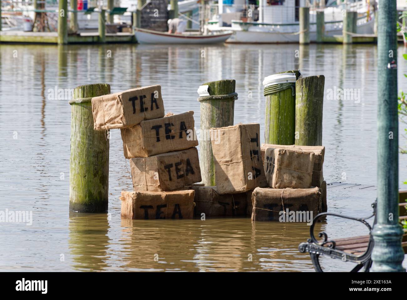 Teeparty-Vertretung. Der Tee wurde im Wasser weggeworfen. Eine moderne Ausstellung von Kisten mit Tee, die ins Meer geworfen werden, wie bei der Boston Tea Party. Stockfoto
