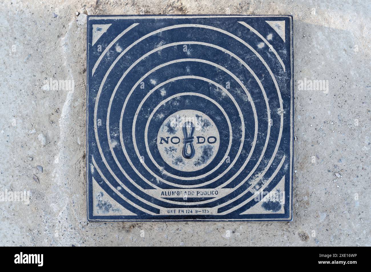 Rund gemusterter Schachtdeckel in Sevilla mit dem ikonischen no8do-Symbol und der Aufschrift „Alumbrado público“ Stockfoto