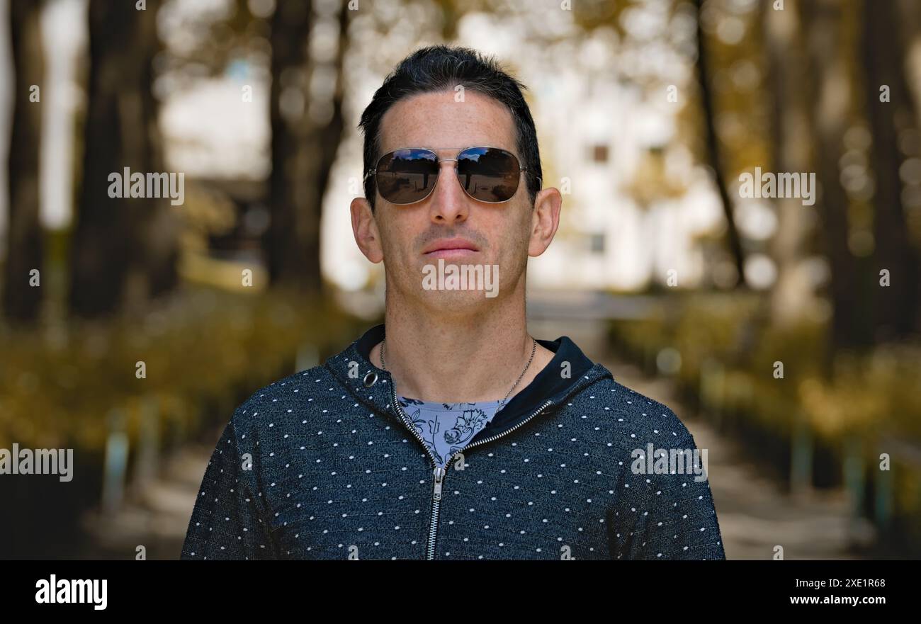 Mediterraner Mann in lässiger Sportbekleidung und Sonnenbrille, Frontporträt, fokussierte Haltung. Stockfoto