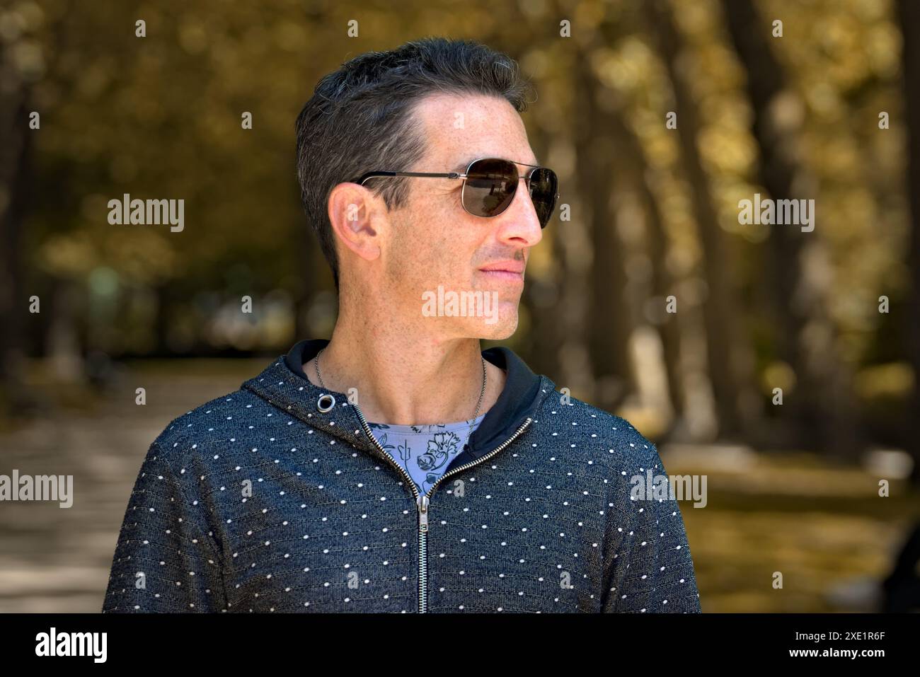Mediterraner Mann in lässiger Sportbekleidung und Sonnenbrille, seitliches Porträt im Freien. Stockfoto