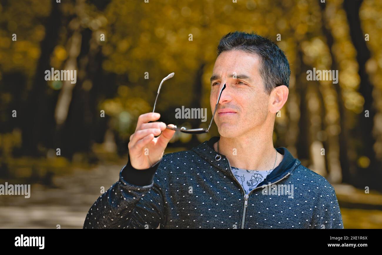 Mediterraner Mann in lässiger Sportkleidung, der Sonnenbrille auszieht. Stockfoto