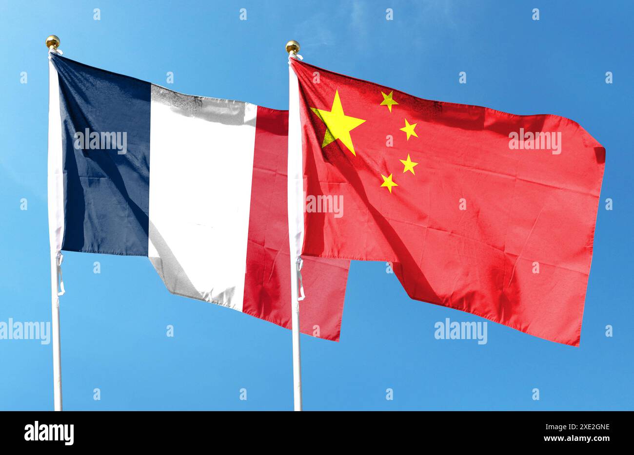 Chinesische Flagge, französische Flagge unter bewölktem Himmel. Fliegen in den Himmel Stockfoto