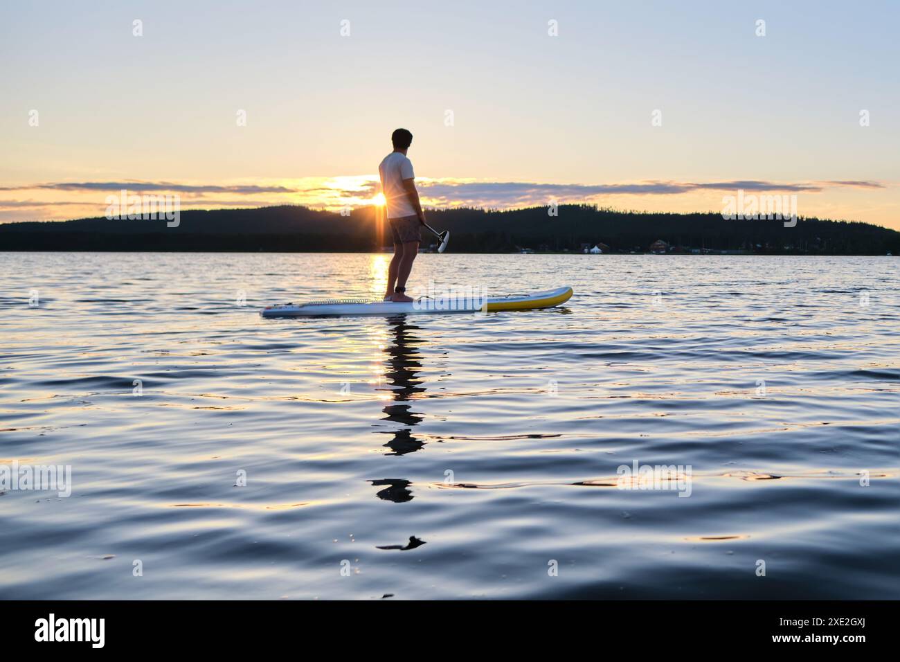 Ein Mann auf einem Paddelbrett in den Sonnenstrahlen. Stockfoto