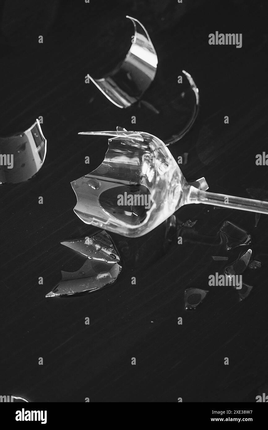 Zerbrochenes Weinglas mit vielen scharfen Scherben auf dem Tisch Stockfoto