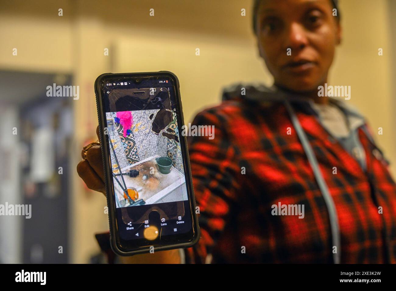 Sacramento, Kalifornien, USA. Februar 2024. TANIKA WILLIAMS hält ihr Handy mit einem Bild des schmutzigen Zustands der Dusche im Greens Hotel während einer Pressekonferenz in Sacramento hoch, wo sie mit ihrer Tochter Makaila, 2, auftrat. Ihre Familie wurde aus ihrem Zimmer im städtischen Obdachlosenheim gesperrt. (Kreditbild: © Rene C. Byer/ZUMA Press Wire) NUR REDAKTIONELLE VERWENDUNG! Nicht für kommerzielle ZWECKE! Stockfoto