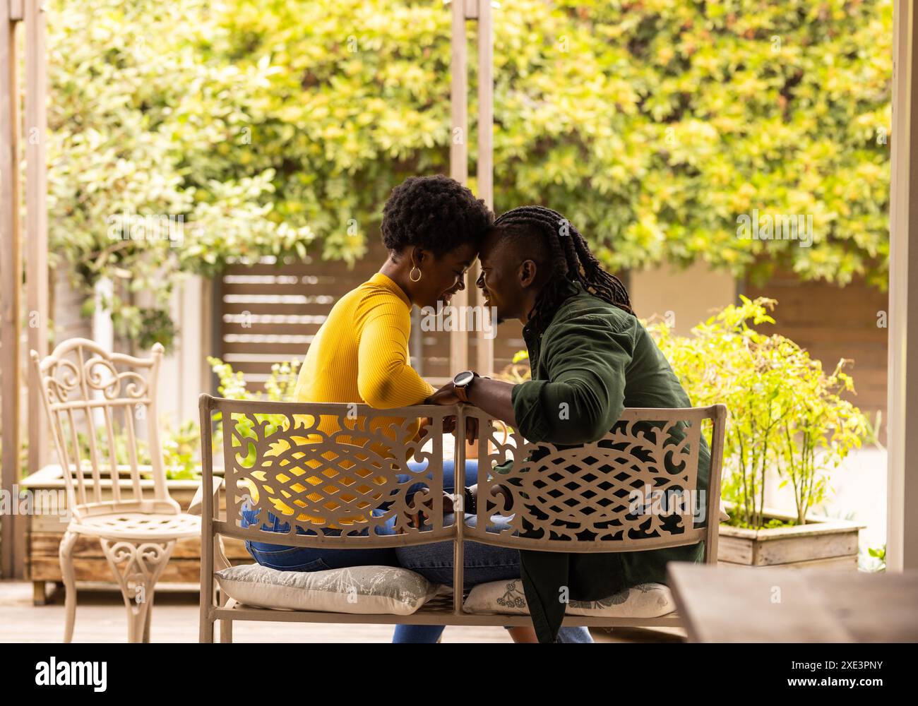 Afroamerikanisches Paar sitzt auf der Bank, teilt intime Momente, lächelt draußen Stockfoto