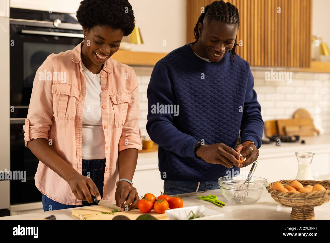 Gemüse hacken und Eier knacken, afroamerikanisches Paar, das Essen in der Küche zubereitet Stockfoto