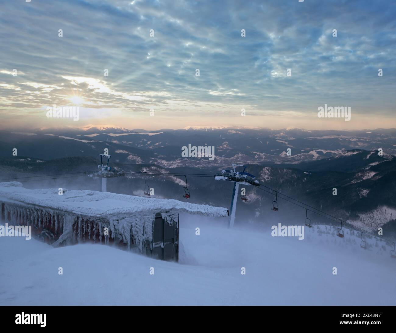 Alpine Resortr Skilift mit Sitzen über den Sonnenuntergang Ski-Pisten in den Bergen bei extrem windigem Wetter Stockfoto