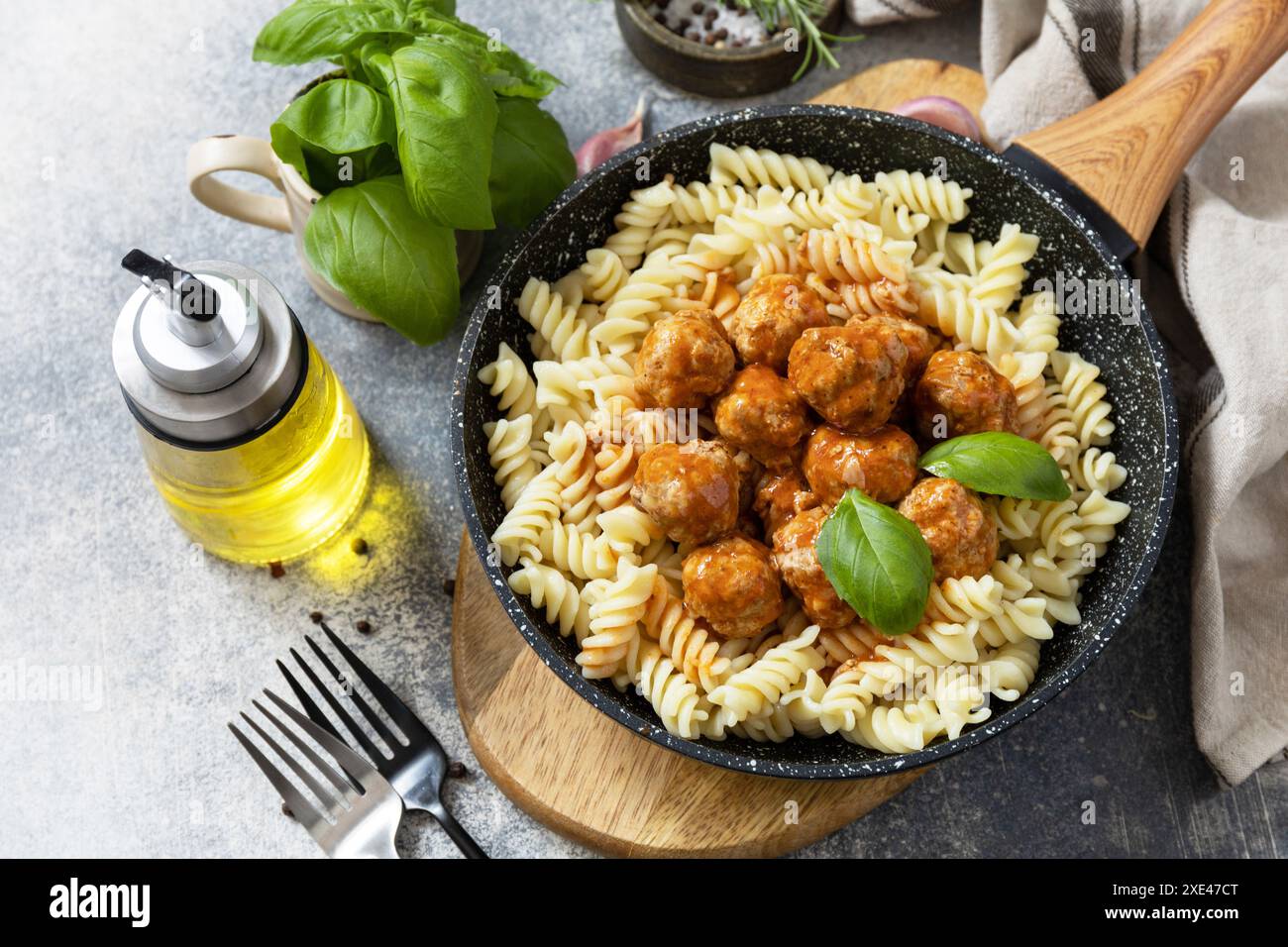 Italienische Küche. Italienische Fusilli-Pasta mit Fleischbällchen in Tomatensauce und Basilikum auf grauem Steingrund. Stockfoto