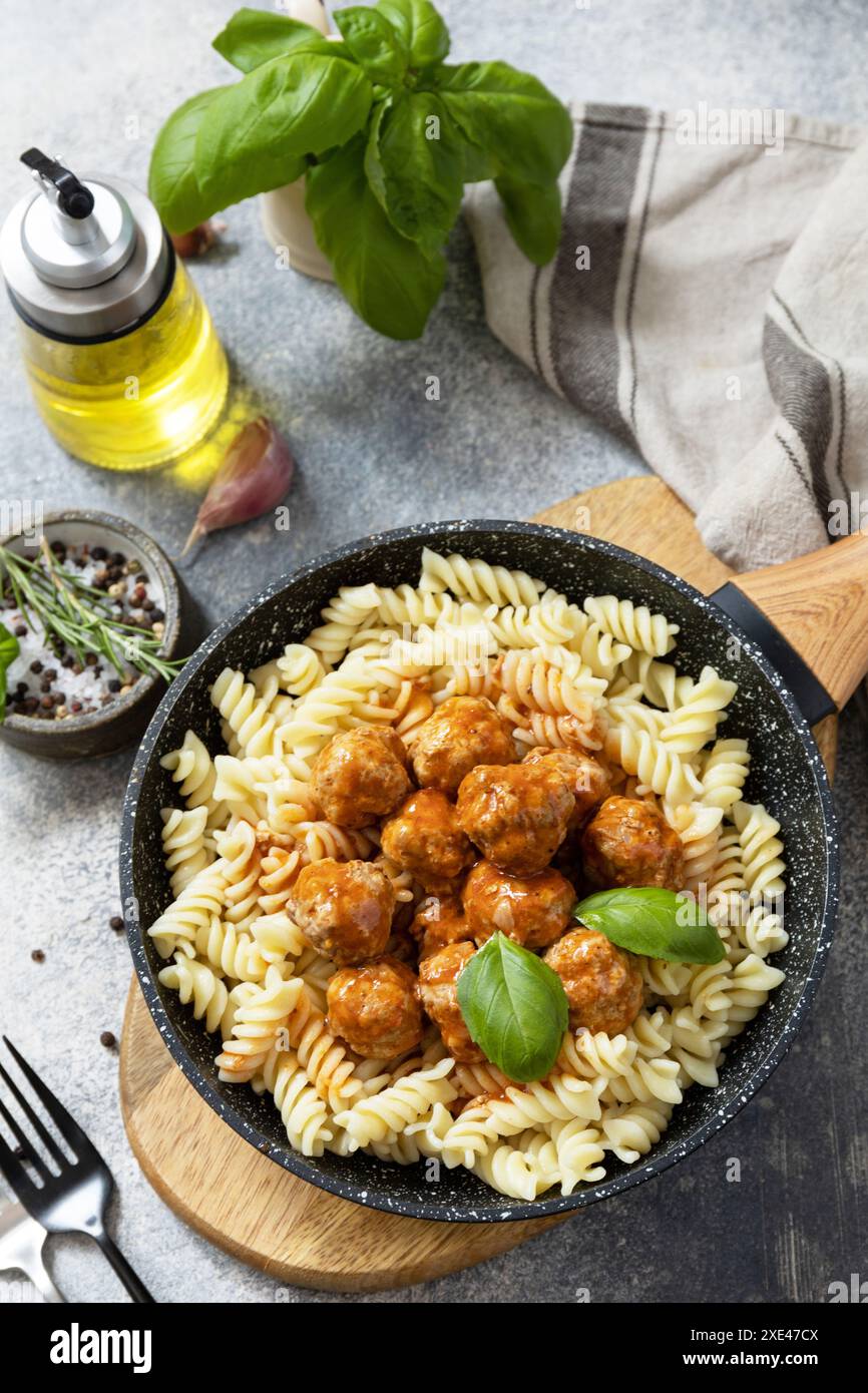 Italienische Küche. Italienische Fusilli-Pasta mit Fleischbällchen in Tomatensauce und Basilikum auf grauem Steingrund. Stockfoto