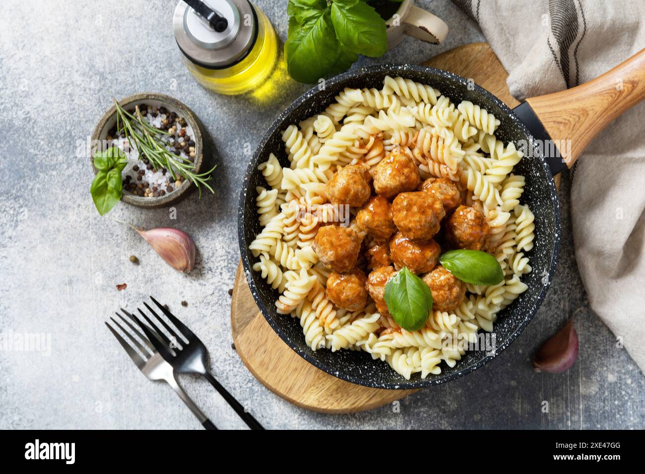 Italienische Küche. Italienische Fusilli-Pasta mit Fleischbällchen in Tomatensauce und Basilikum auf grauem Steingrund. Flach liegend, Draufsicht. Stockfoto