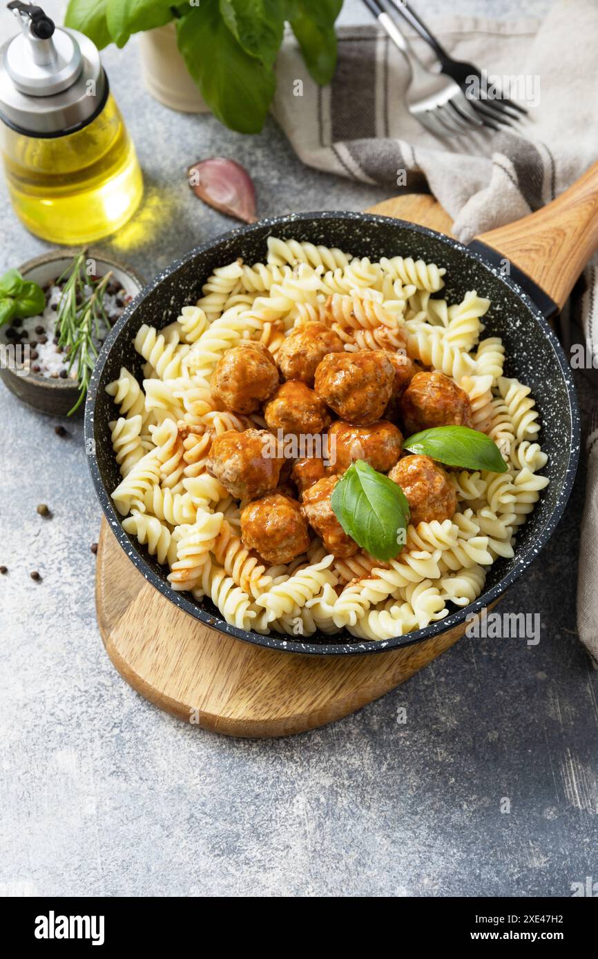 Italienische Küche. Italienische Fusilli-Pasta mit Fleischbällchen in Tomatensauce und Basilikum auf grauem Steingrund. Speicherplatz kopieren. Stockfoto