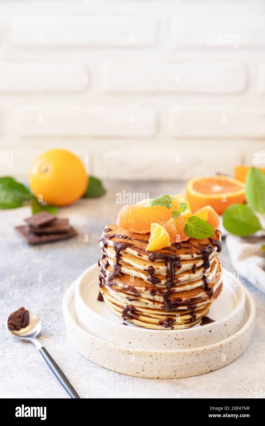Pancake Day feiern, gesundes Frühstück. Köstliche hausgemachte amerikanische Bananenpfannkuchen mit Schokolade und roter Orange auf grauen s Stockfoto