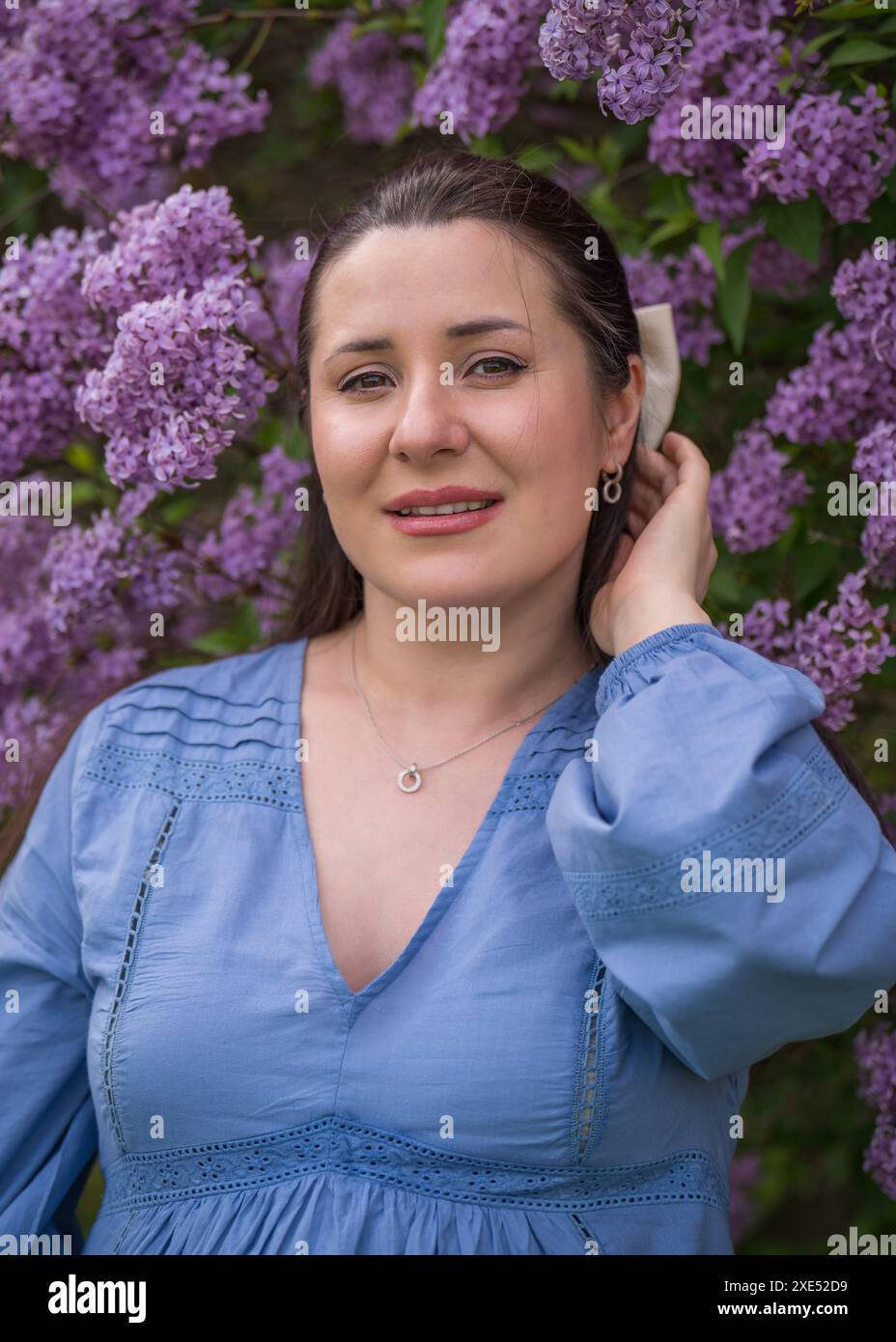 Porträt eines süßen, glücklichen Mädchens. Schwangere Frau nahe Flieder. Nahaufnahme. Schwangerschaft. Warten auf das Baby. Stockfoto