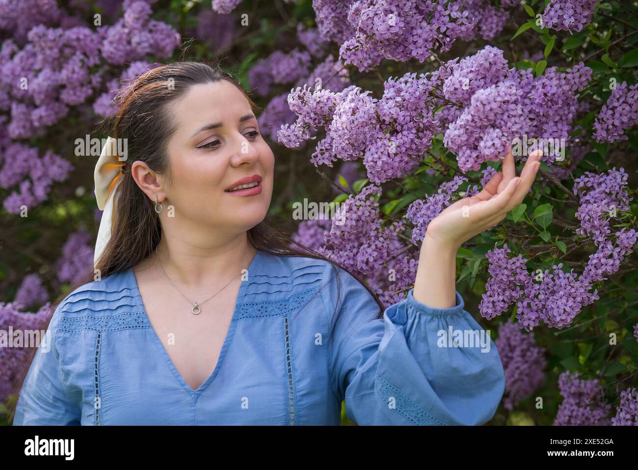 Porträt eines süßen, glücklichen Mädchens. Schwangere Frau nahe Flieder. Nahaufnahme. Schwangerschaft. Warten auf das Baby. Stockfoto