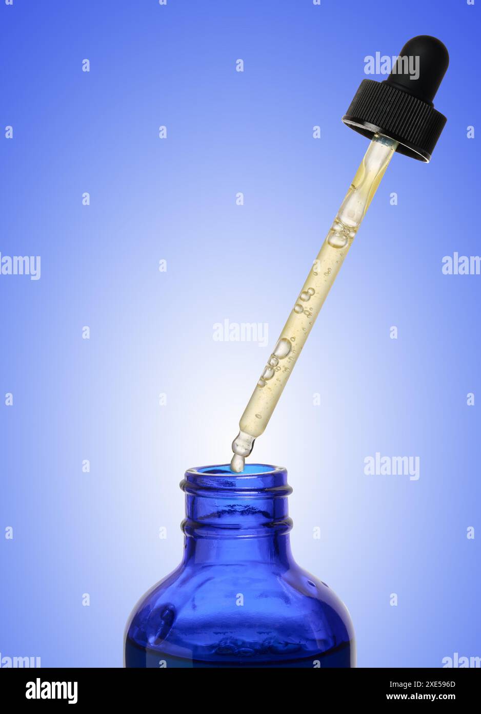 Eine glasblaue Flasche mit Tropfer auf blauem Hintergrund, ein Behälter für kosmetische Produkte. Stockfoto
