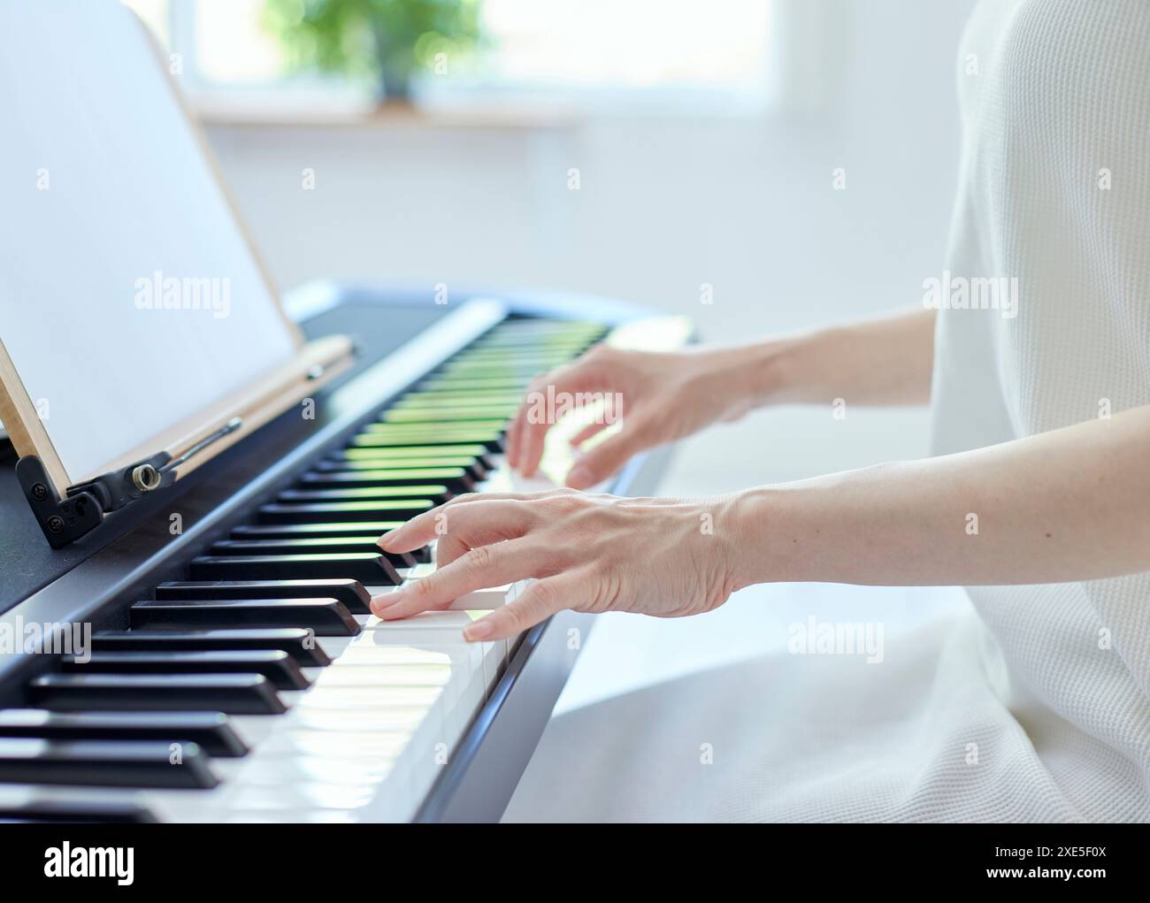 Japanerin spielt Klavier im Wohnzimmer Stockfoto