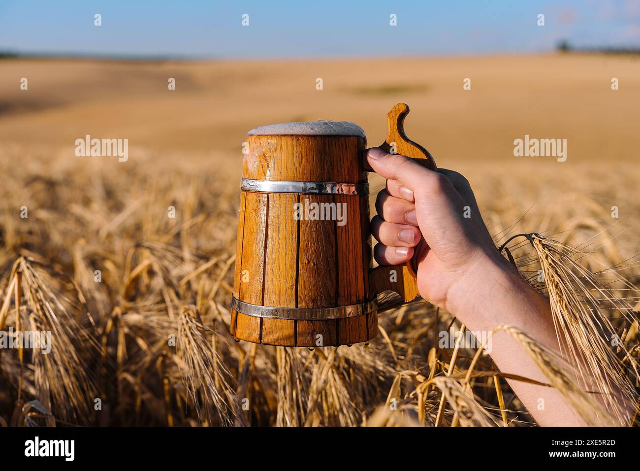 Die Hand hält einen Holzbecher mit Bier Stockfoto