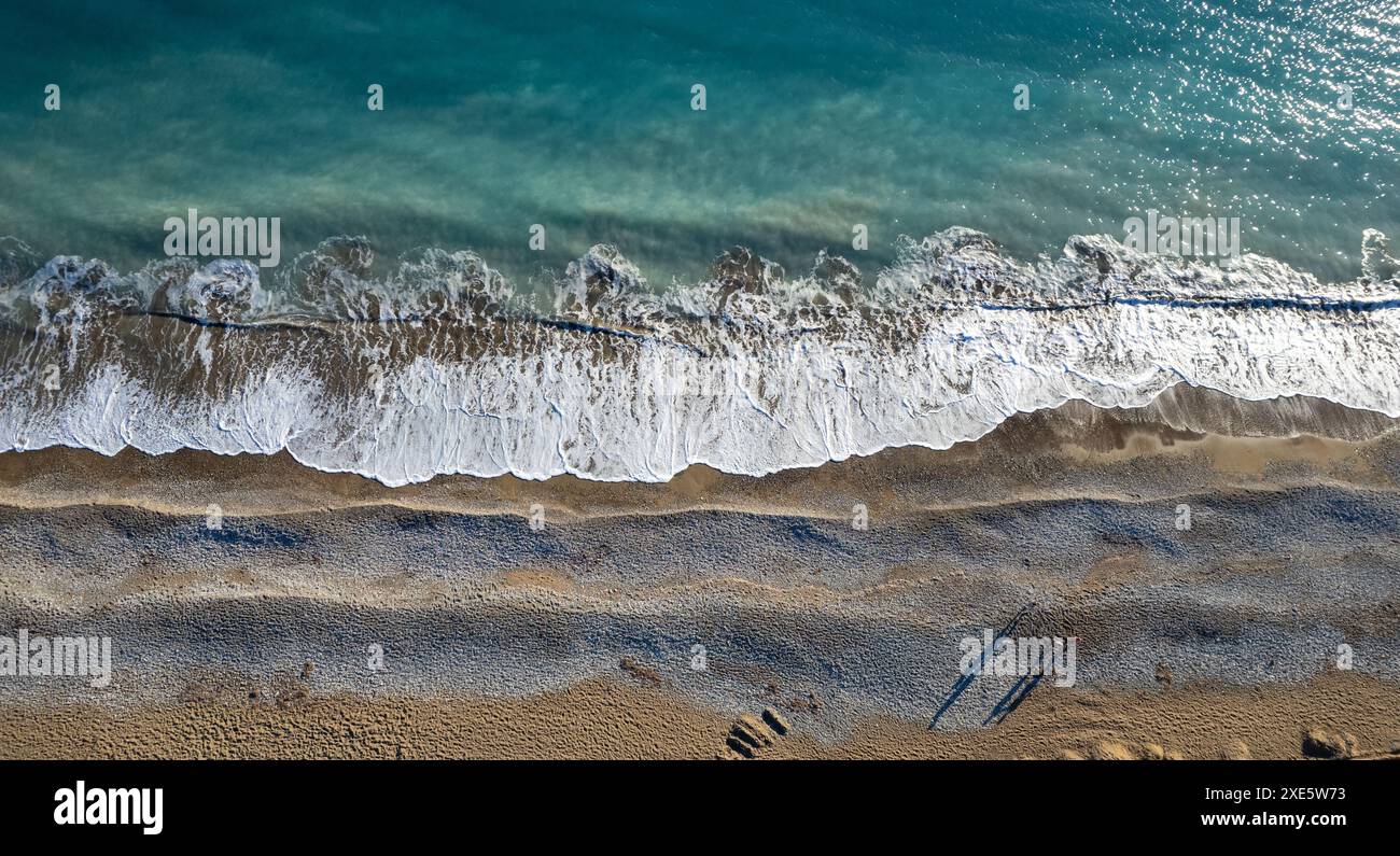 Aus der Drohne sehen Sie eine Person, die an einem Strand auf Sand läuft. Stürmische Wellen idyllischer Strand im Winter Stockfoto