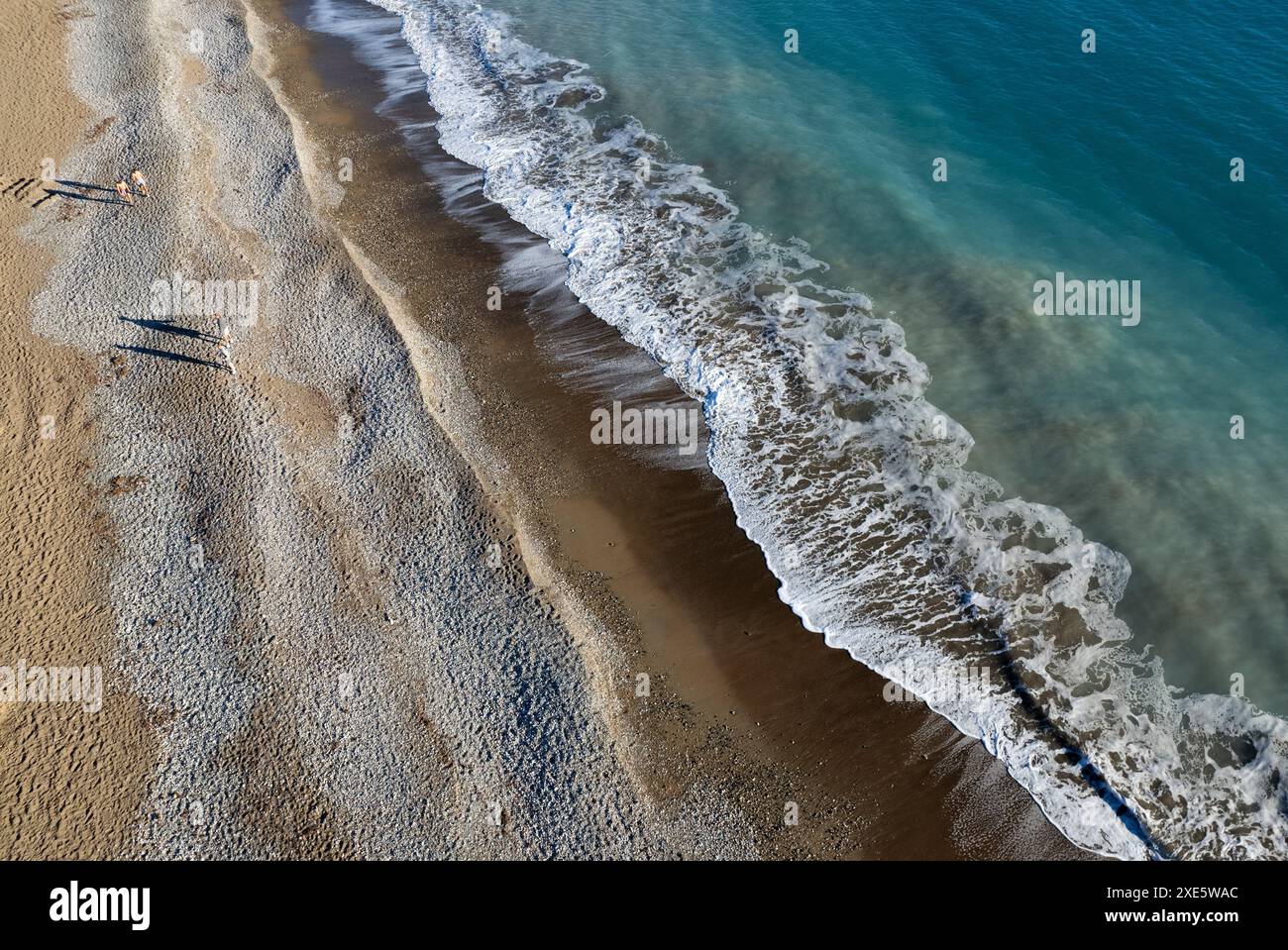 Aus der Drohne sehen Sie eine Person, die an einem Strand auf Sand läuft. Stürmische Wellen idyllischer Strand im Winter Stockfoto
