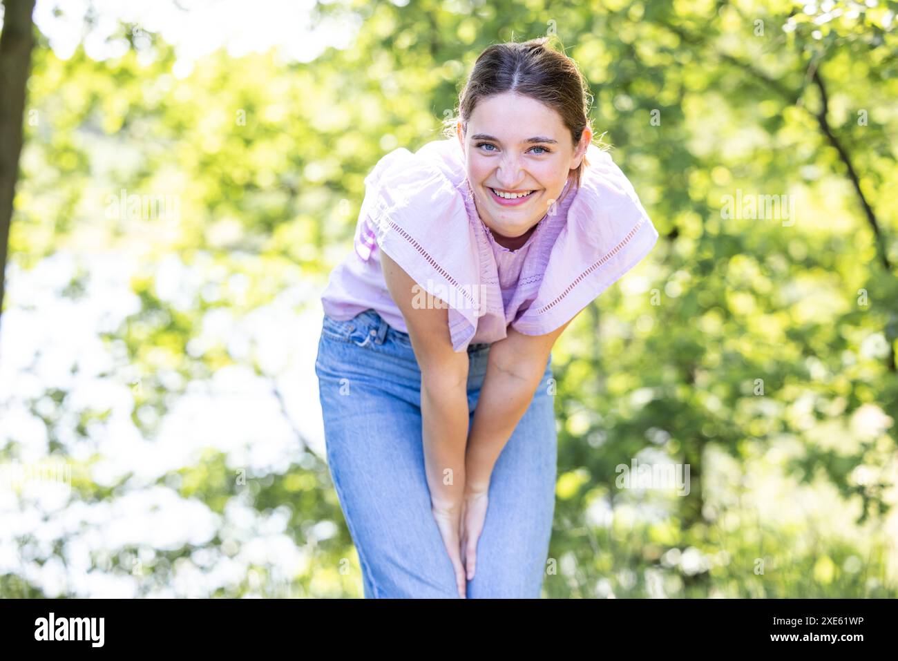 Die verspielte junge Frau lehnt sich im Park nach vorne Stockfoto
