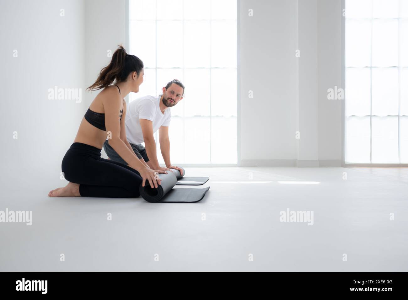 Paare machen Yoga-Aktivitäten zu Hause, Rollen die Yogamatte hoch Stockfoto