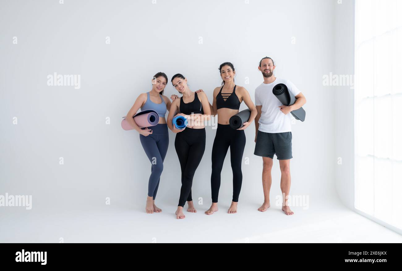 Eine Gruppe weiblicher und männlicher Athleten stand und plauderte gütlich im Studio, bevor sie mit der Yoga-Klasse begannen. Stockfoto