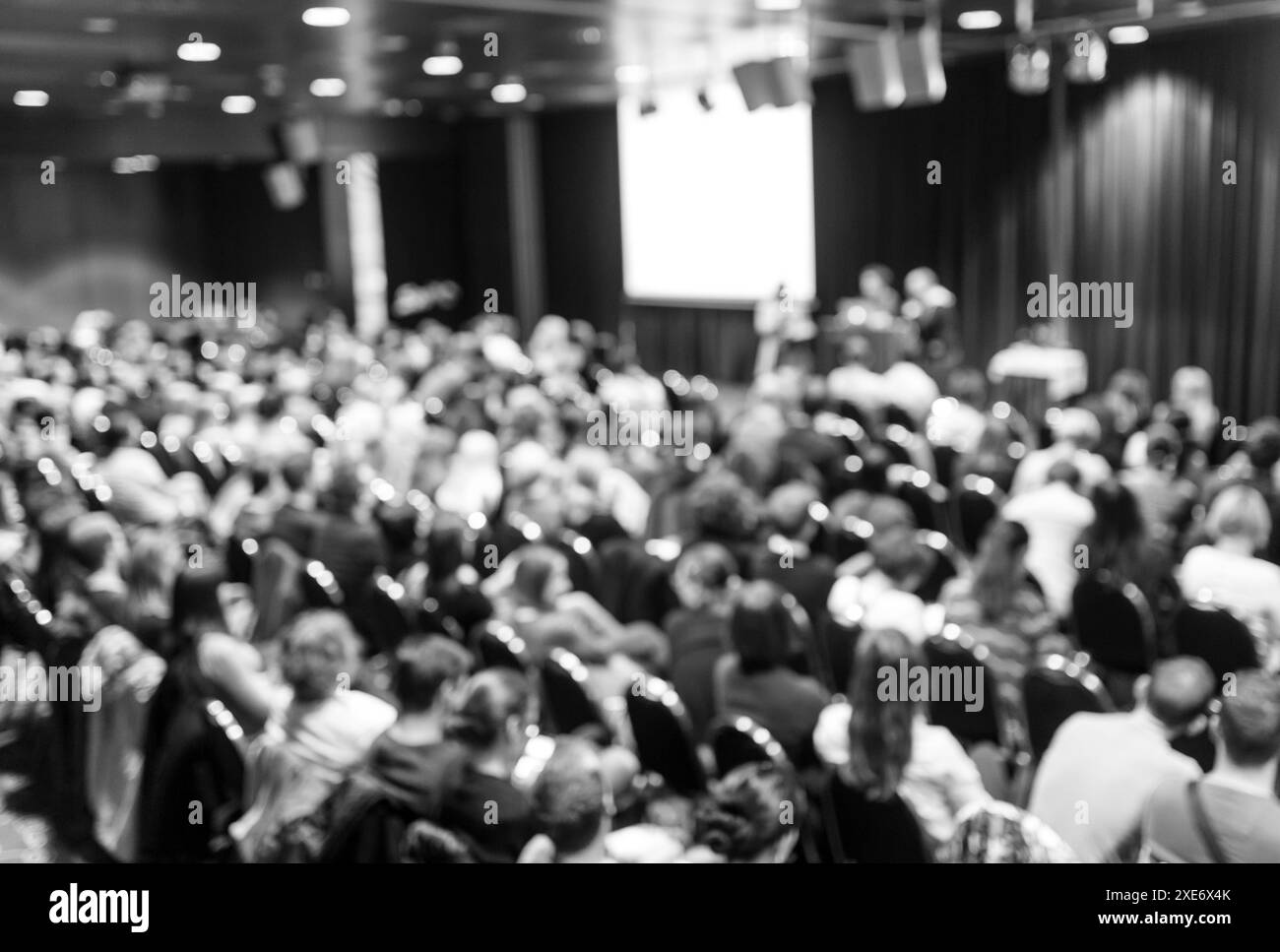 Symposium für Wirtschaft und Unternehmertum. Redner hält einen Vortrag bei einem Geschäftstreffen. Publikum im Konferenzsaal. Rückansicht eines nicht erkannten Teilnehmers im Publikum. Schwarz-weiß. Stockfoto